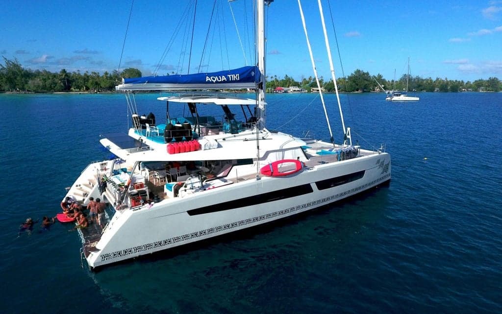 Aquatiki III catamaran floats through the Tuamotu Archipelago, diving sites like Fakarava South Pass where hundreds of grey reef sharks gather under incoming tide