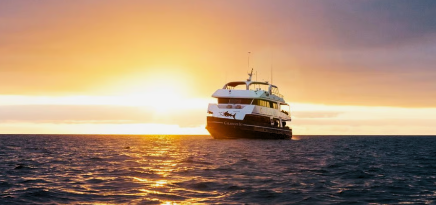 The Galápagos Sky liveaboard dive boat sailing on the ocean during sunset, illustrating the premium experience of Galápagos Liveaboard Diving.