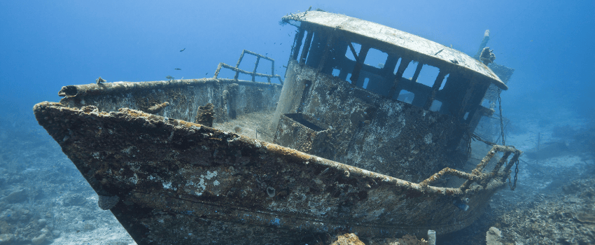 The coral-encrusted wreck of the Mr. Bud shrimping boat sitting on a sandy bottom in Roatan, Honduras, a top site for scuba diving in July.