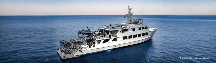 The Nautilus Explorer liveaboard vessel cruising on the open Pacific Ocean, known for its oversized dive deck and photography facilities 