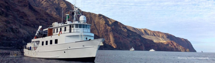 The Nautilus Undersea liveaboard anchored near the rugged, volcanic coastline of Socorro Island, ideal for film crews and small groups. 