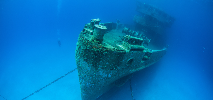 A massive shipwreck, the Kittewake, sits on a sandy seafloor in Grand Cayman. This ship was sunk intentionally to act as an artificial reef and as an attraction for scuba divers. 