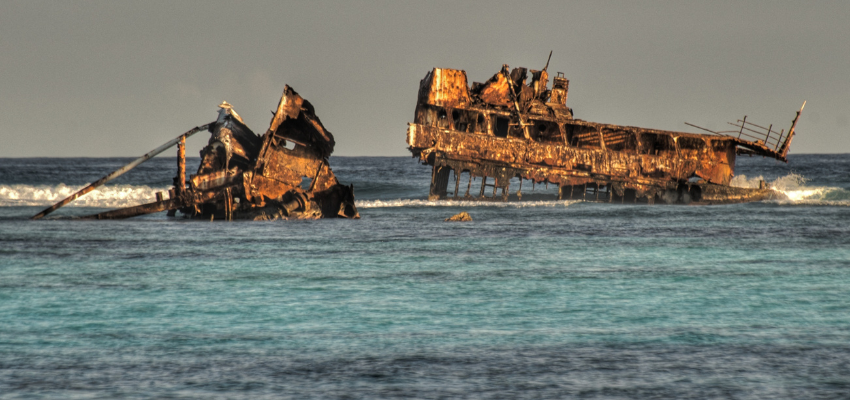 The rusted, metal remains of the Astron shipwreck are broken in two and protruding above the water's surface near the coastline of Punta Cana. 