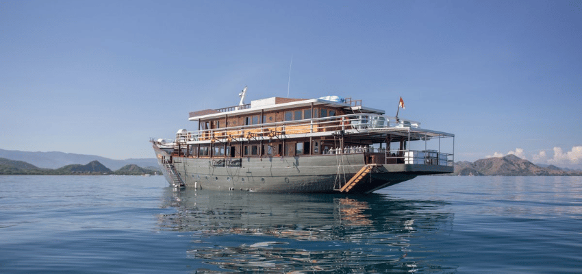 Emperor Harmoni Liveaboard Indonesia Large-format premium wooden Phinisi Emperor Harmoni anchored in calm waters.