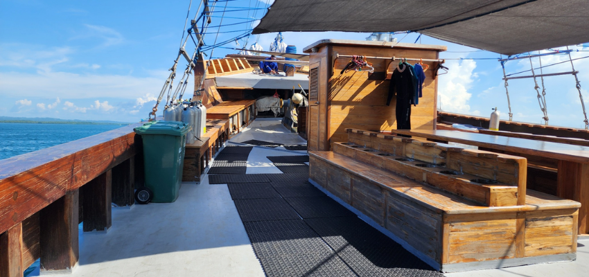 sundeck Dancing Wind Liveaboard Indonesia Shaded open-air lounge area on Dancing Wind showcasing fine dining table settings for private charter guests.