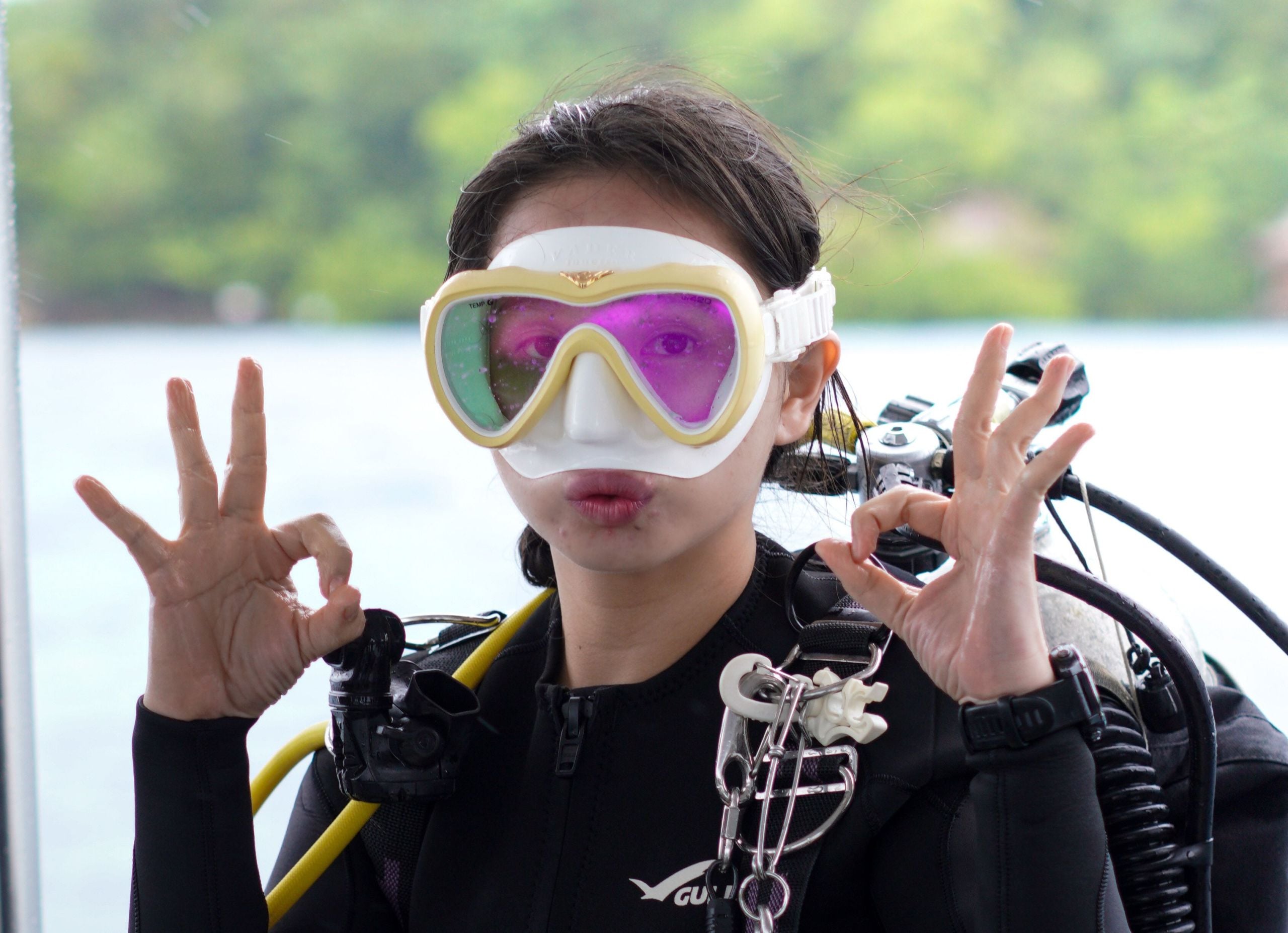 Woman scuba diver in full gear giving OK sign before a dive