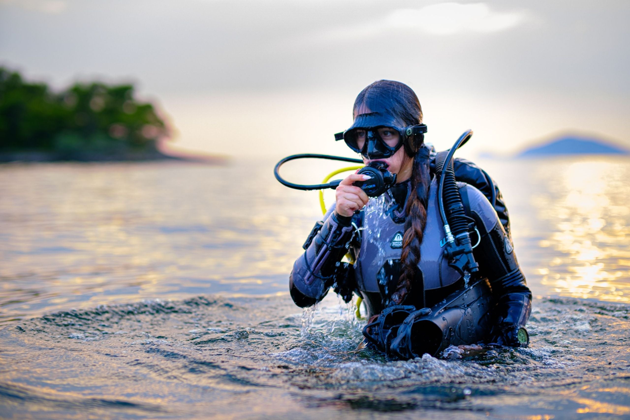 Woman scuba diver surfacing after a dive at sunset